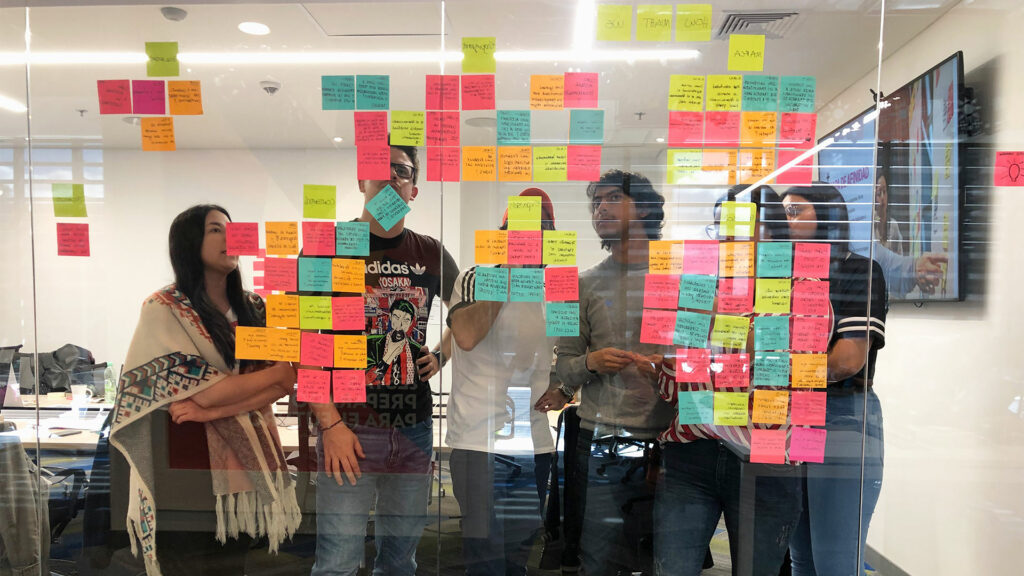 People of design sprint looking at the glass with Post-Its